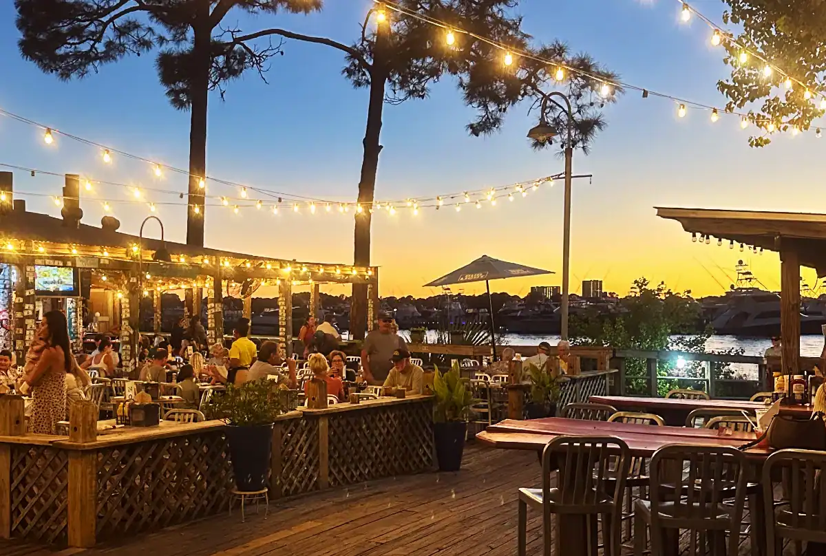 Al fresco dining at Baytowne Wharf with string lights and sunset views over the water.