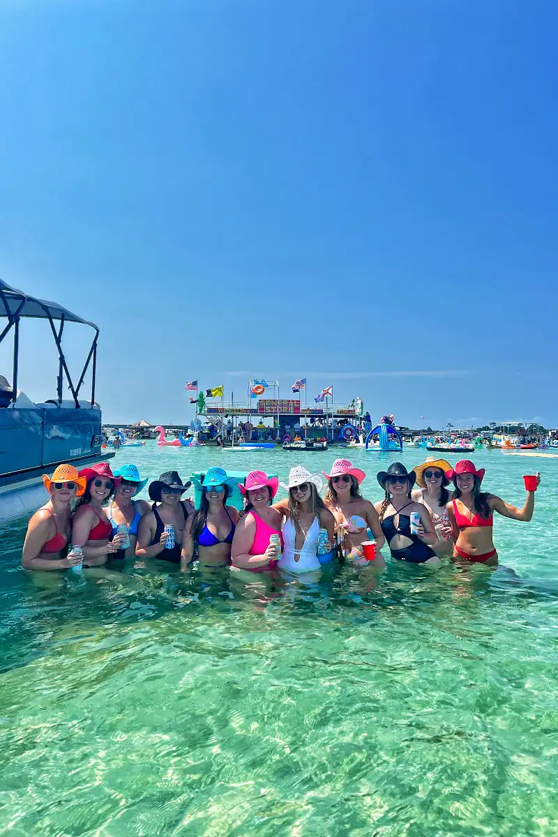 Bachelorettes in colorful swimsuits and hats at Crab Island near a pontoon
