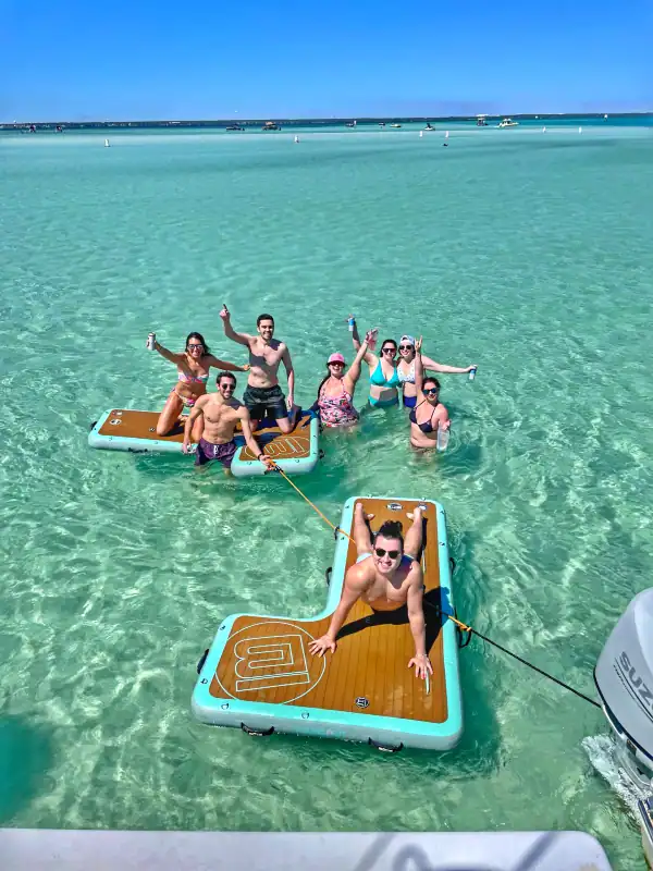 Group of people on BOTE floats with Crab Island Luxury Adventures, playing at Crab Island next to their catamaran