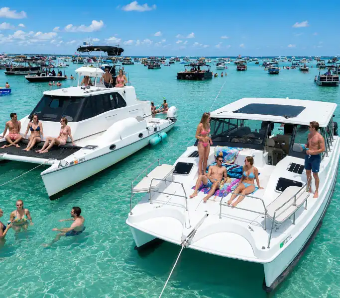 Two white catamarans anchored at Crab Island with people sitting on the decks