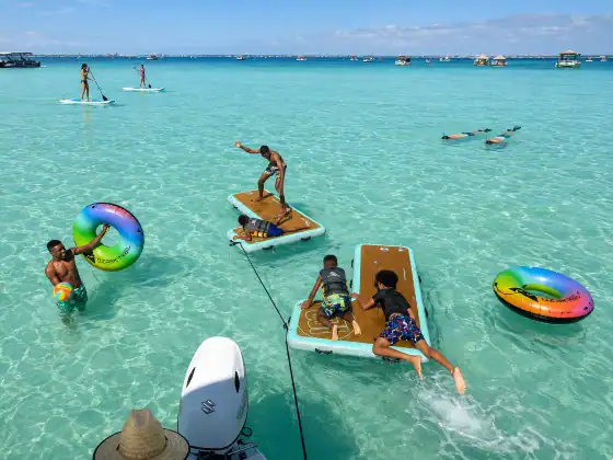 A large family at Crab Island. Some are playing on floats, some paddleboarding, and others snorkeling.