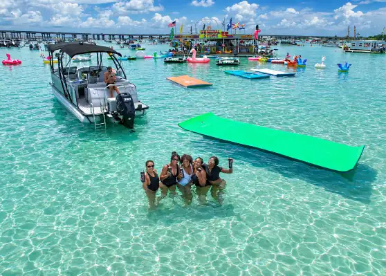 Bachelorettes playing in the water at Crab Island with their Crab Island Luxury Adventure Pontoon Rental in the background.