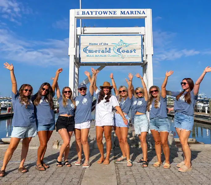 bachelorettes standing in front of the Baytowne Marina sign getting ready to board their charter to Crab Island