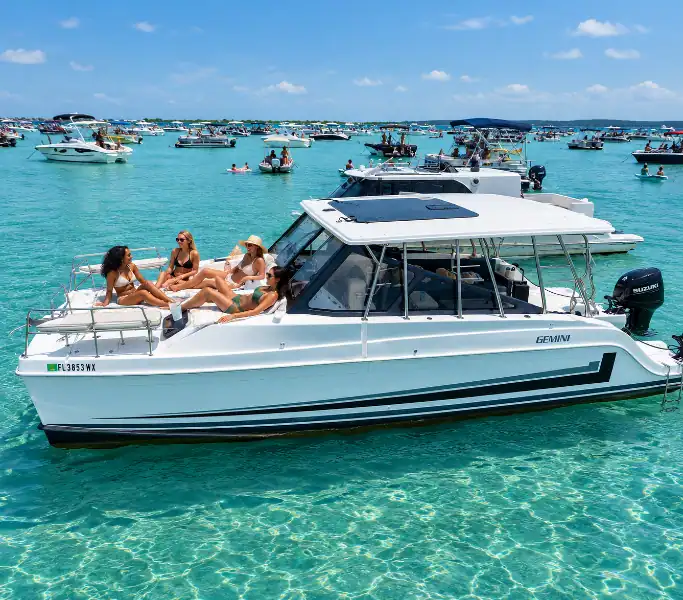 Gemini Catamaran anchored at Crab Island with four ladies lounging on the front deck.